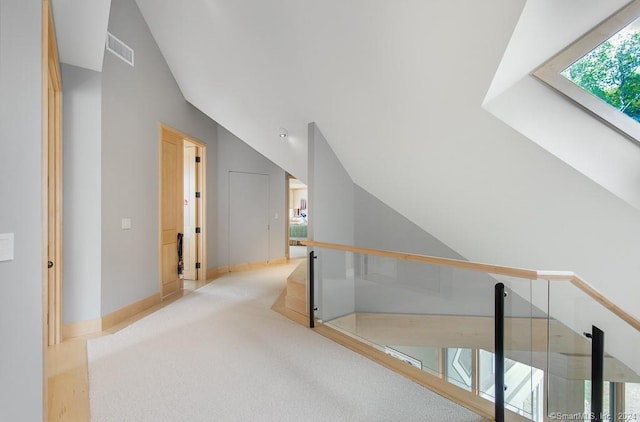 corridor featuring light colored carpet and vaulted ceiling