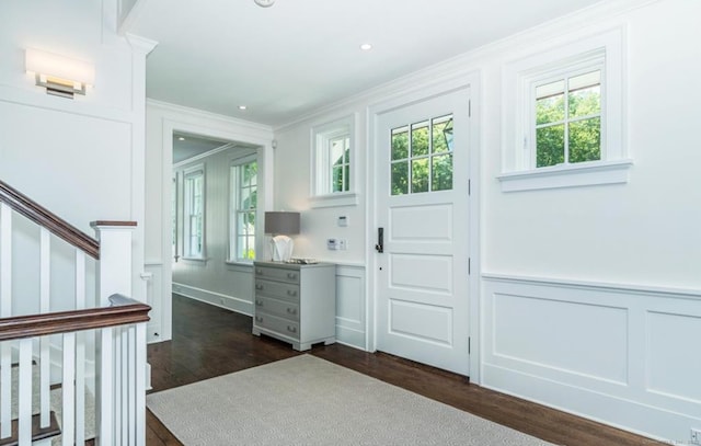 doorway featuring a decorative wall, a wainscoted wall, ornamental molding, stairway, and dark wood finished floors