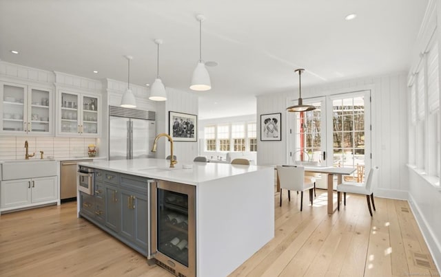 kitchen featuring wine cooler, a sink, appliances with stainless steel finishes, and white cabinetry