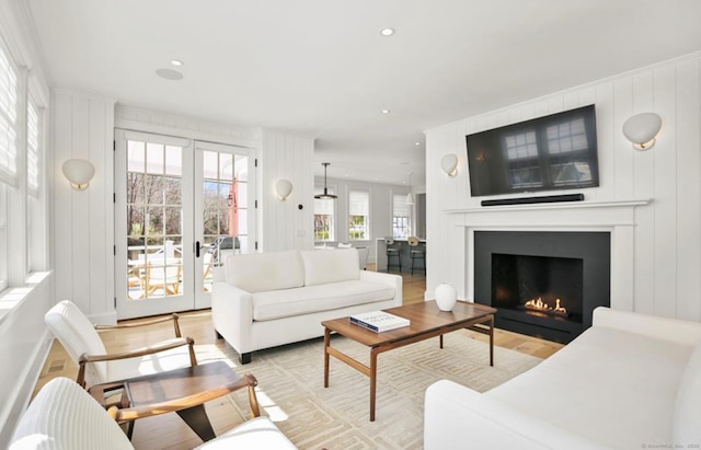 living room with light wood-type flooring, french doors, a fireplace, and recessed lighting