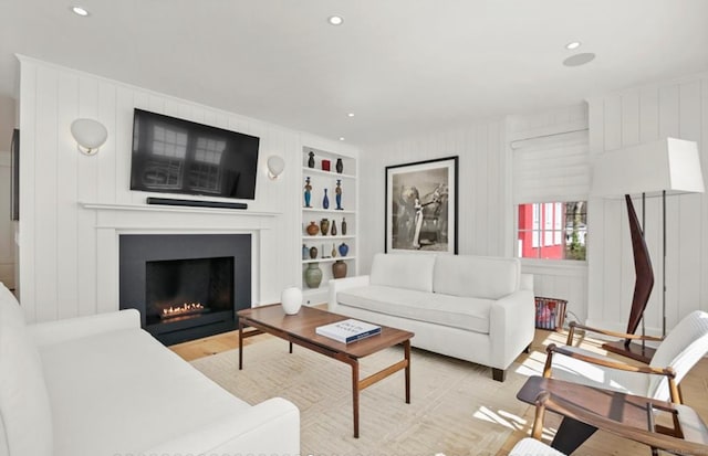 living area with a large fireplace, built in shelves, and recessed lighting