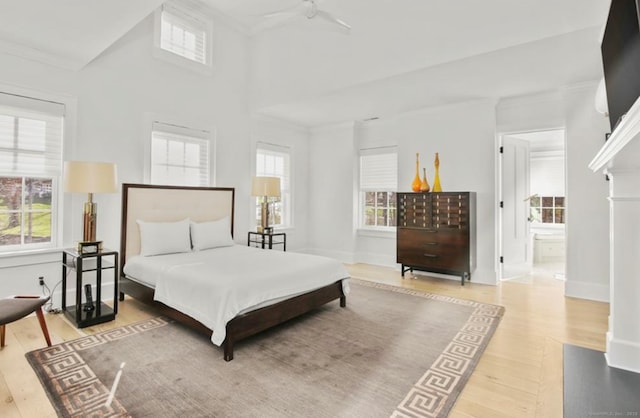 bedroom with baseboards, ensuite bathroom, wood finished floors, and crown molding