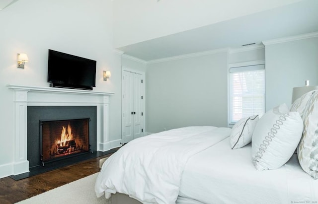 bedroom featuring a lit fireplace, visible vents, ornamental molding, and dark wood-type flooring