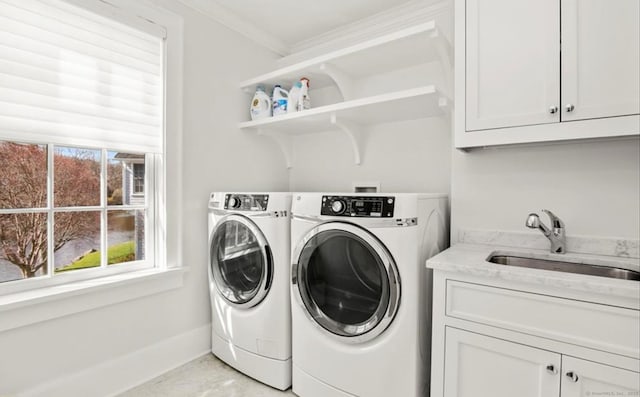 washroom featuring cabinet space, baseboards, ornamental molding, washer and dryer, and a sink