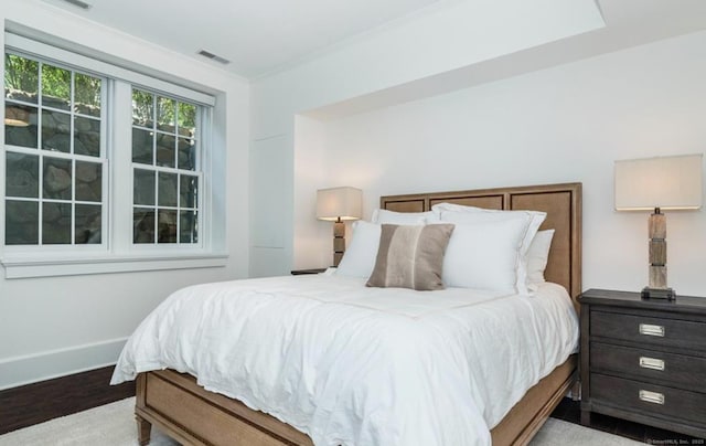 bedroom with ornamental molding, light wood-style flooring, visible vents, and baseboards