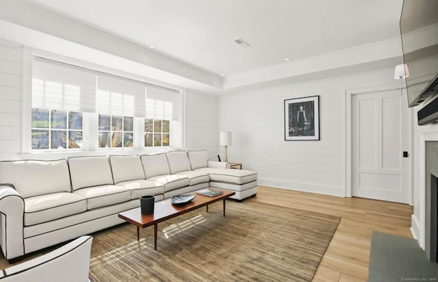 living room with a fireplace with flush hearth, a raised ceiling, wood finished floors, and recessed lighting