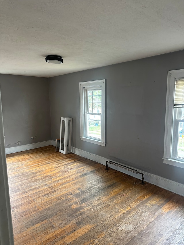 empty room featuring a baseboard radiator and wood-type flooring