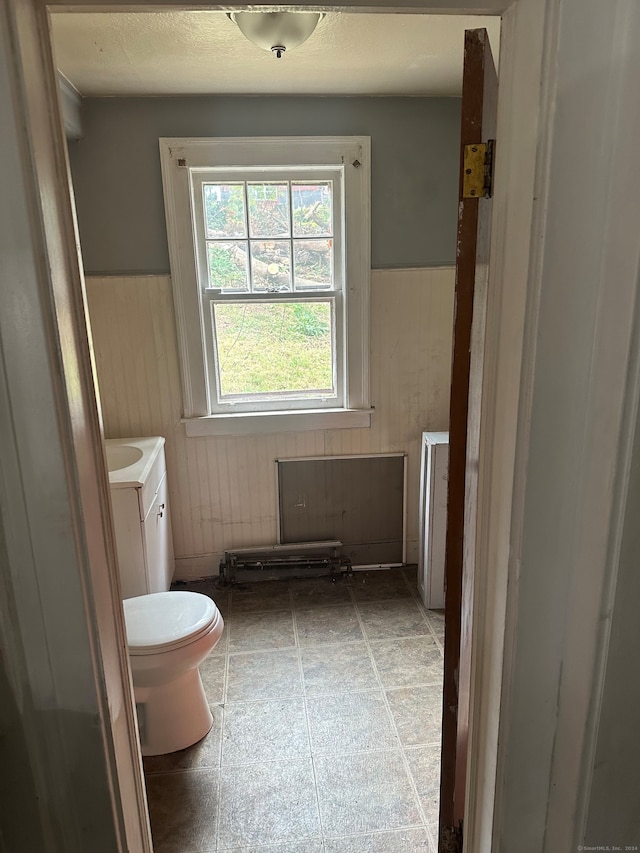 bathroom featuring vanity, wood walls, and toilet