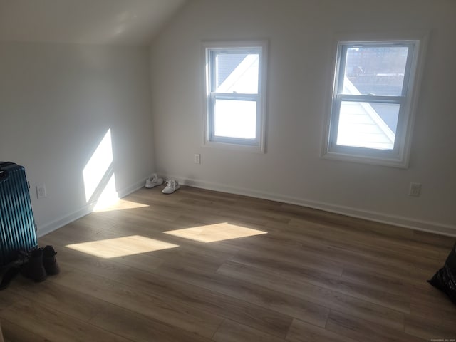 bonus room with dark hardwood / wood-style flooring, a healthy amount of sunlight, and vaulted ceiling