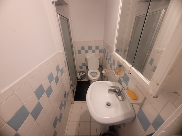 bathroom featuring tile walls, tile floors, sink, and toilet