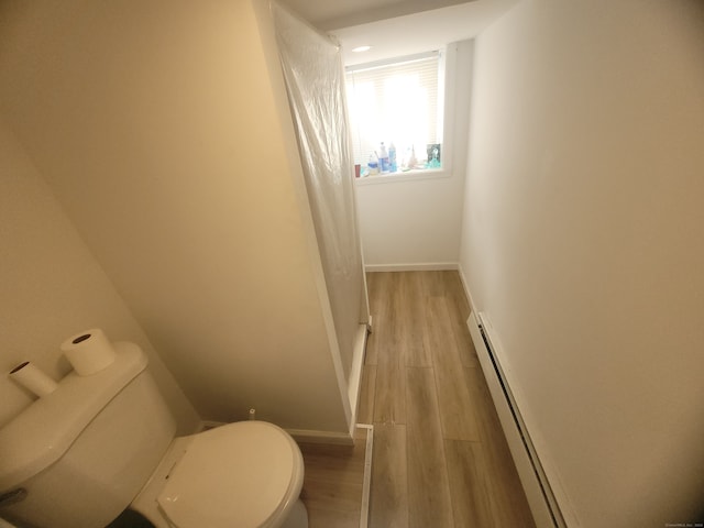 bathroom with wood-type flooring, a baseboard heating unit, and toilet