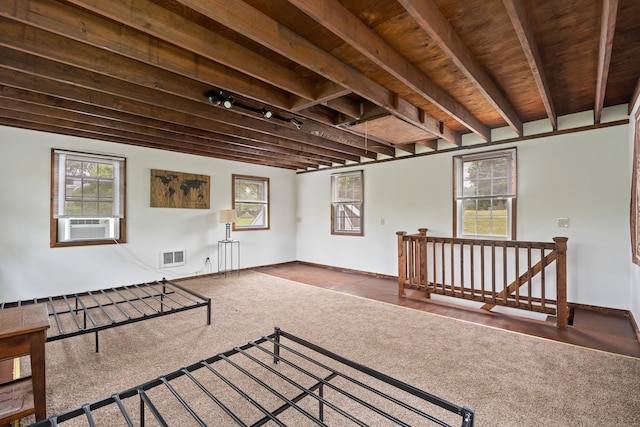 interior space with rail lighting, wood ceiling, dark carpet, and beamed ceiling