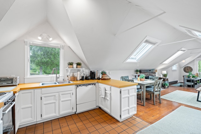 kitchen with vaulted ceiling with skylight, dishwasher, sink, and white cabinets