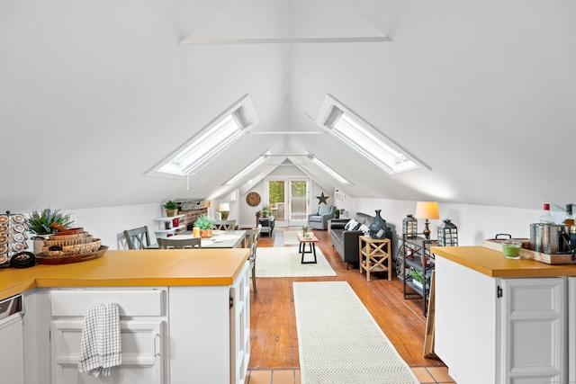 kitchen with lofted ceiling with skylight, light hardwood / wood-style flooring, and white cabinetry