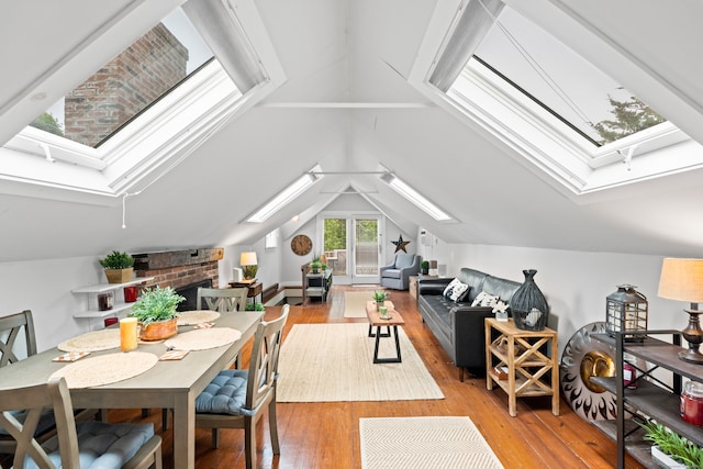 interior space featuring lofted ceiling with skylight, light hardwood / wood-style flooring, and a fireplace