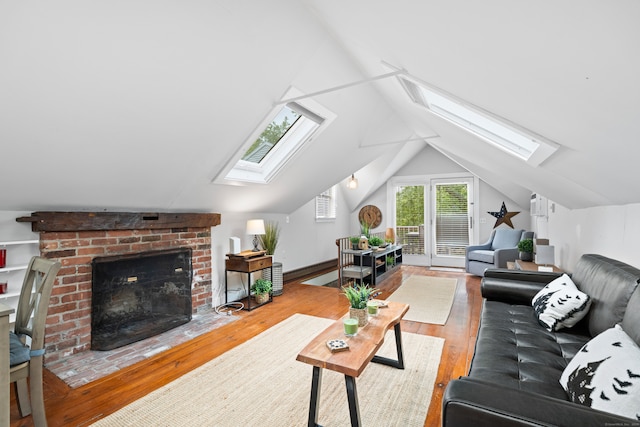 living room with a fireplace, lofted ceiling with skylight, and wood-type flooring