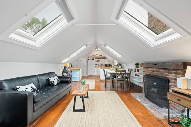 living room featuring lofted ceiling with skylight and light hardwood / wood-style flooring