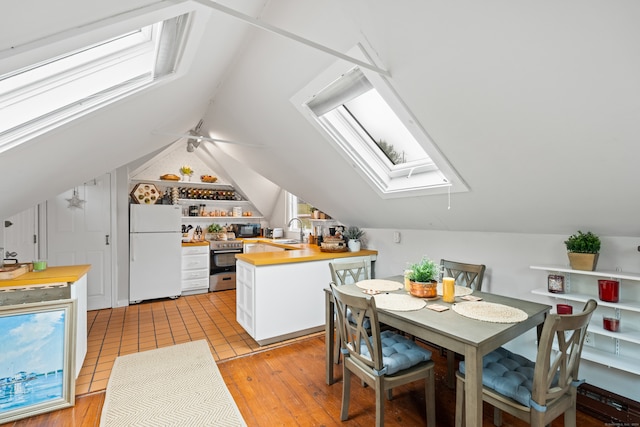 dining room featuring light hardwood / wood-style flooring, sink, and lofted ceiling with skylight