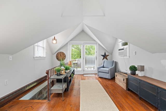 living area featuring lofted ceiling, a wall unit AC, dark hardwood / wood-style floors, and baseboard heating