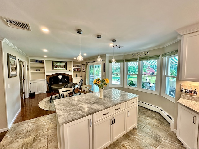 kitchen with a baseboard heating unit, hanging light fixtures, white cabinetry, a center island, and light tile patterned floors