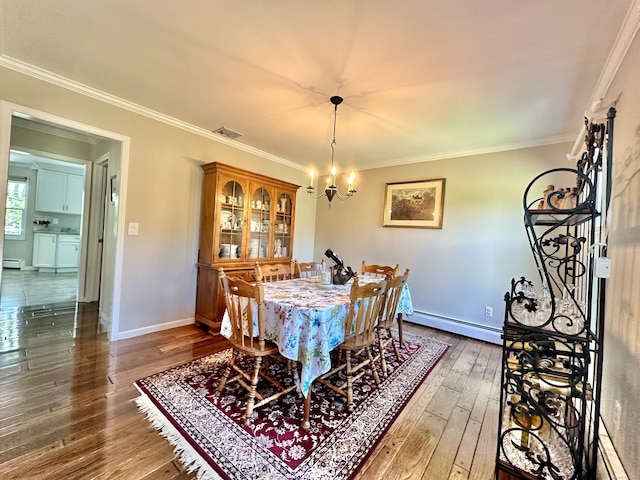 dining area with hardwood / wood-style floors, crown molding, baseboard heating, and an inviting chandelier