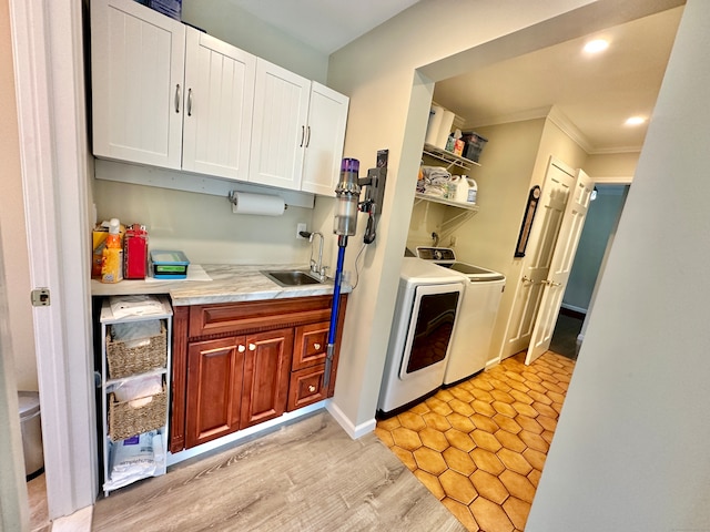 kitchen with white cabinetry, light tile patterned floors, washing machine and dryer, ornamental molding, and sink