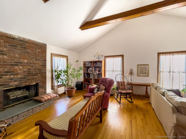 living room with beamed ceiling, a brick fireplace, light wood-type flooring, and high vaulted ceiling