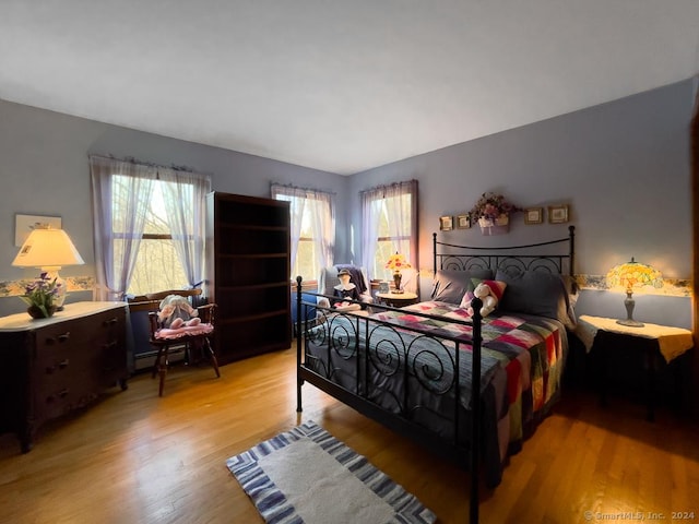 bedroom featuring light hardwood / wood-style floors and a baseboard heating unit