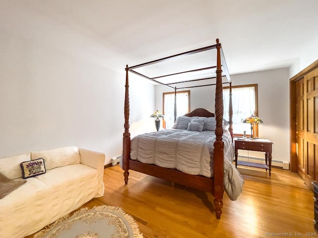 bedroom with light wood-type flooring and a baseboard heating unit