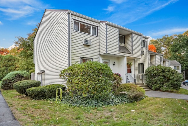 view of front of house with a front lawn and a wall mounted air conditioner