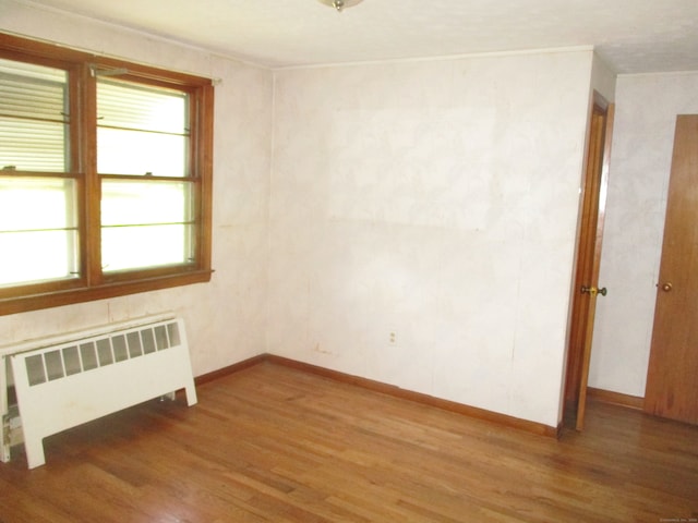 unfurnished room with radiator heating unit and hardwood / wood-style flooring