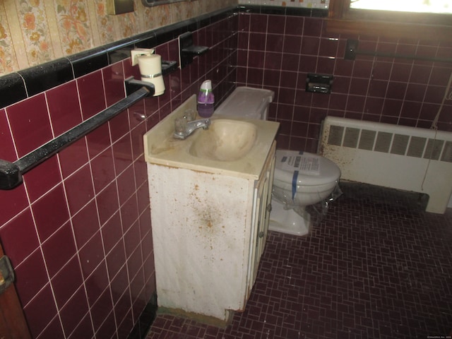 bathroom with tile walls, vanity, toilet, and radiator