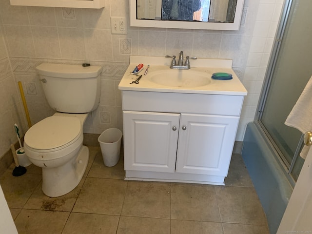 full bathroom featuring tile walls, shower / bath combination with glass door, tile floors, toilet, and vanity