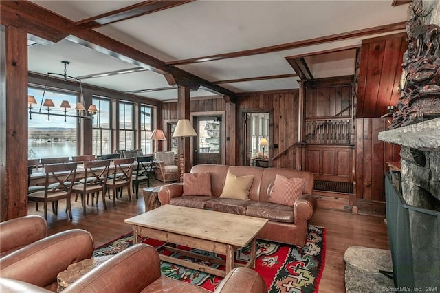 living room with a fireplace, wooden walls, dark hardwood / wood-style flooring, an inviting chandelier, and beam ceiling