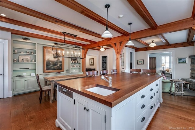 kitchen featuring a center island with sink, sink, wood-type flooring, and white cabinets