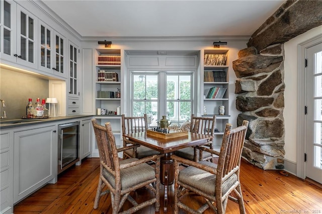 dining room with ornamental molding, wine cooler, and hardwood / wood-style flooring