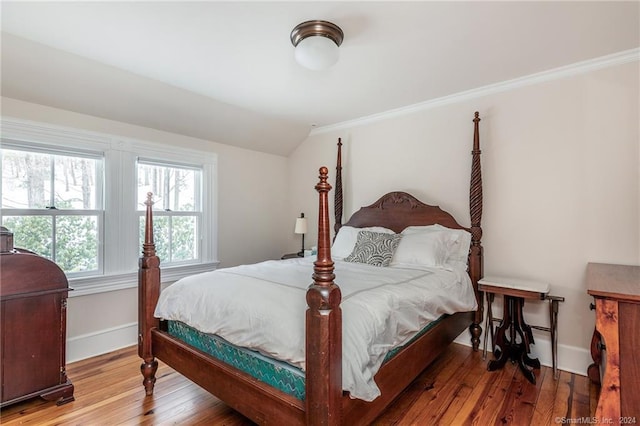 bedroom featuring lofted ceiling, ornamental molding, and hardwood / wood-style floors