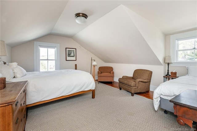 bedroom with multiple windows, vaulted ceiling, and hardwood / wood-style flooring