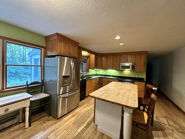 kitchen featuring sink, wooden counters, a textured ceiling, light wood-type flooring, and stainless steel appliances