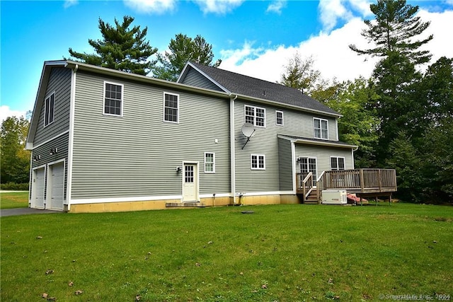 back of property with a deck, a yard, and a garage