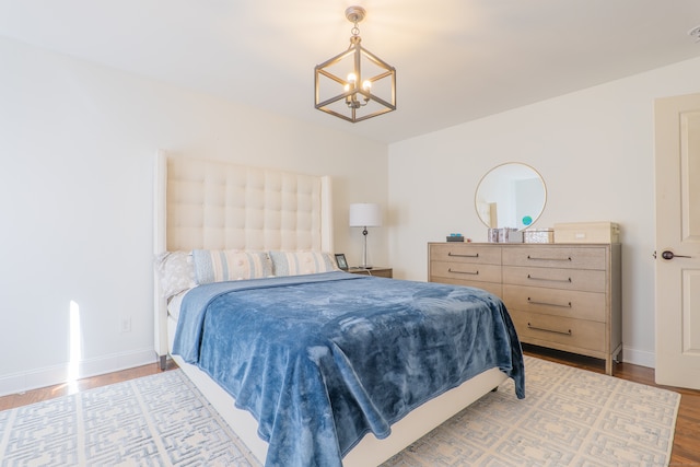 bedroom with wood-type flooring and an inviting chandelier