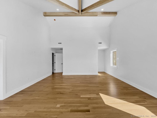 unfurnished living room with beam ceiling, wood-type flooring, and high vaulted ceiling