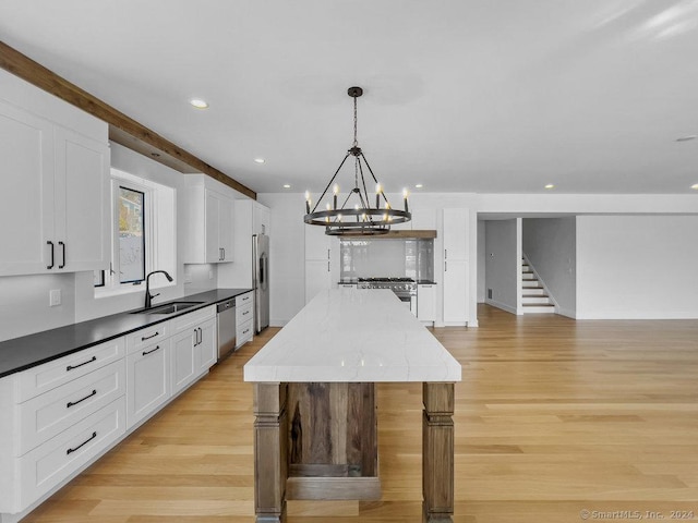 kitchen featuring decorative light fixtures, a center island, sink, appliances with stainless steel finishes, and white cabinets