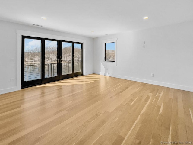 empty room featuring french doors and light hardwood / wood-style flooring