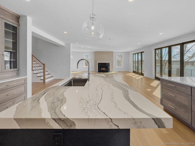 kitchen with light stone countertops, a fireplace, sink, and hanging light fixtures