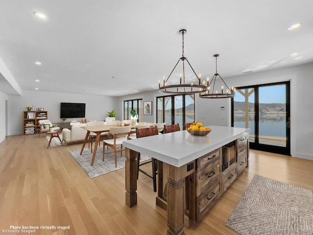 kitchen with a wealth of natural light, a kitchen island, light hardwood / wood-style flooring, and decorative light fixtures