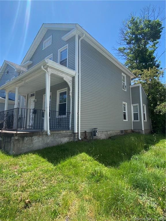 rear view of house with covered porch and a lawn