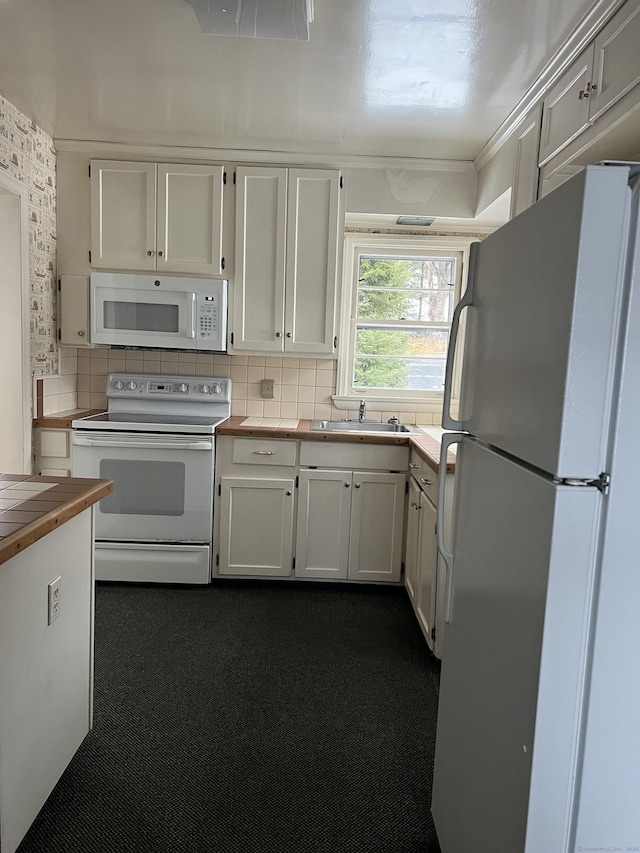 kitchen with sink, tasteful backsplash, tile counters, white appliances, and white cabinets