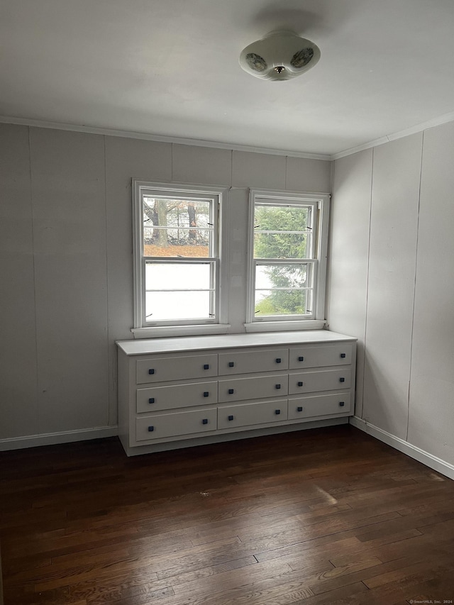 empty room with dark hardwood / wood-style flooring and ornamental molding