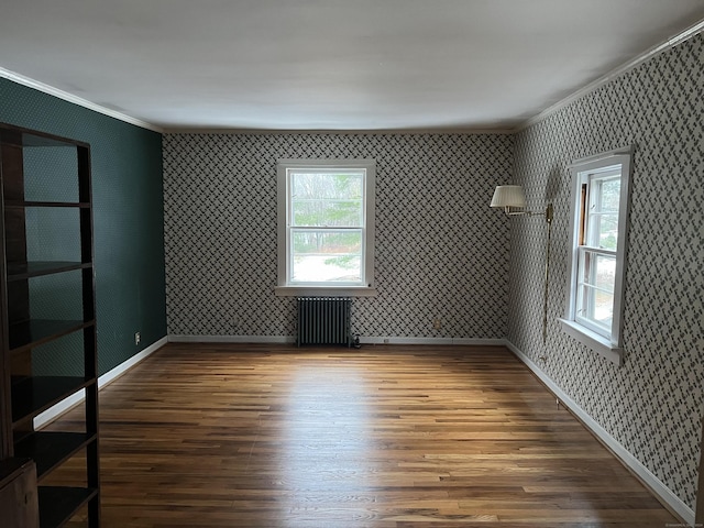 empty room featuring crown molding, wood-type flooring, and radiator